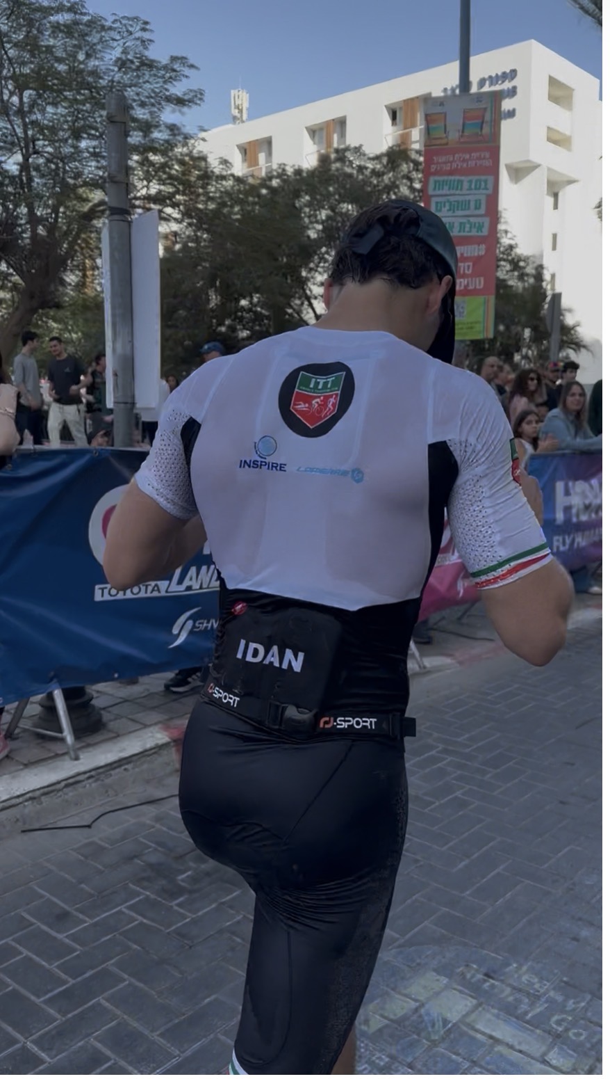 עידן בקטע הריצה של תחרות ISRAMAN באילת, לובש חליפת טריאתלון עם השם שלו על החגורה